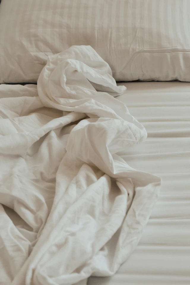 Soft white bed linen and pillows in natural light.