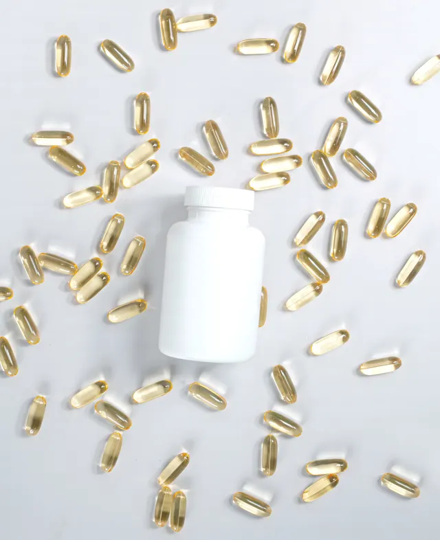 Golden softgel capsules arranged around a plain white bottle.